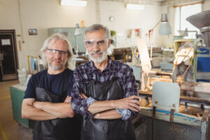 Team of 2 male glass blowers with arms crossed